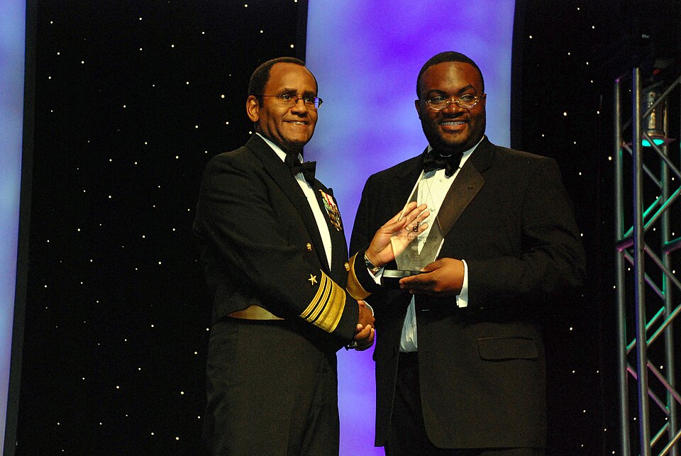 Two Black honorees receiving an award at a formal gala celebration